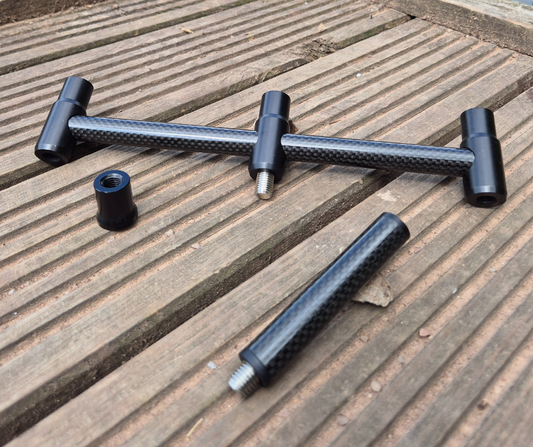 Black carbon bankware, including a buzz bar and stage stand insert laid flat on a wooden platform